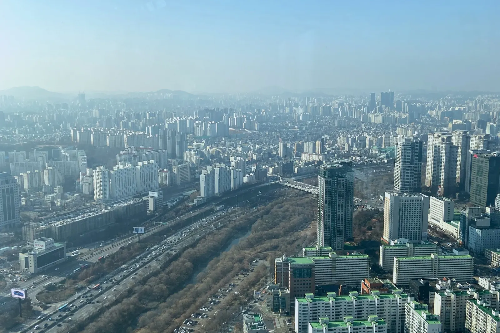 높은 곳에서 내려다본 고속도로와 하천변 숲, 양옆의 아파트 단지